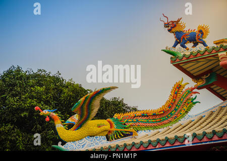 Bella dragone cinese capo-unicorn e cinese phoenix statue sul tetto nel tempio cinese con drammatico sfondo del cielo. Foto Stock