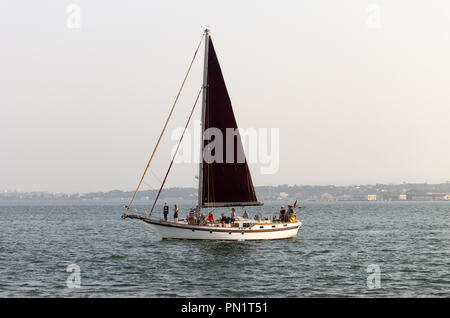 Una barca a vela passa da nel fiume con diverse persone a bordo. Foto Stock