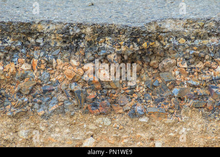 Lo strato di asfalto con delle rocce e del suolo dopo la frana. Foto Stock