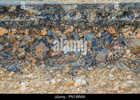 Lo strato di asfalto con delle rocce e del suolo dopo la frana. Foto Stock