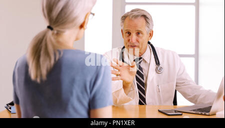 Fiducioso Senior medico a discutere di procedura chirurgica con donna anziana paziente Foto Stock