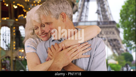 Senior affettuoso marito e moglie abbracciando vicino alla Torre Eiffel Foto Stock