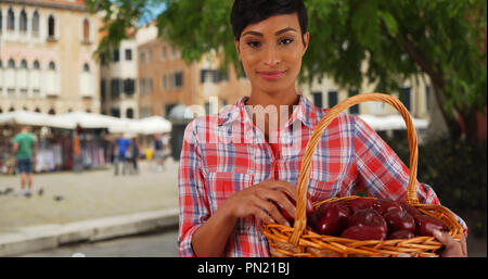 Sorridente ritratto di African American donna giardiniere cestello di contenimento di mele Foto Stock