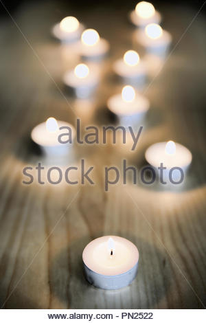 Tealight candele accese su un pavimento di legno Foto Stock