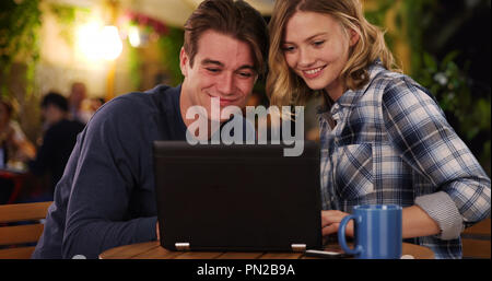 Allegro l uomo e la donna di guardare video sul computer portatile a sorridere e ridere Foto Stock