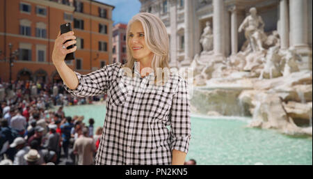 Donna anziana prende un selfie presso la Fontana di Trevi a Roma Foto Stock