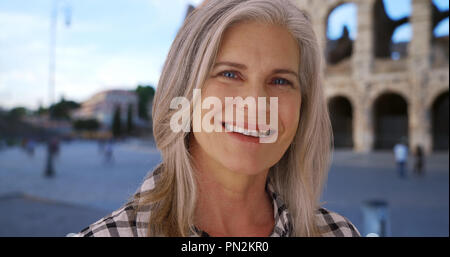 Sorridente femmina bianco senior gode di se stessa nella parte anteriore del Colosseo romano Foto Stock