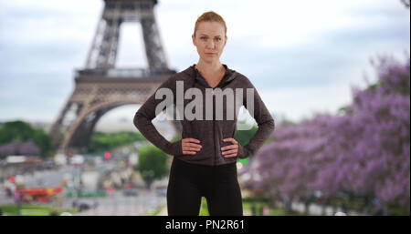 Determinata la donna bianca in posa con le mani a fianchi con torre Eiffel in background Foto Stock