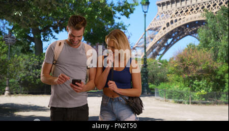 Felice e coppia attraente usando la mappa sullo smartphone a Parigi Foto Stock