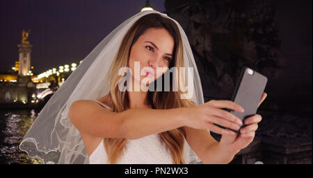 Sposa gioiosa prendendo selfies divertimento a Parigi di notte Foto Stock