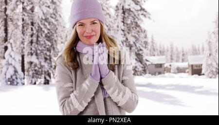 Di mezza età donna caucasica godendo la neve esterno cabina in un resort Foto Stock