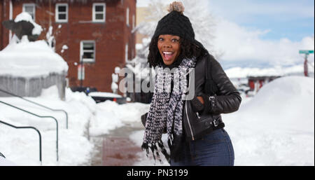 Carino donna nera gira intorno a sorridere alla telecamera fuori nella neve Foto Stock