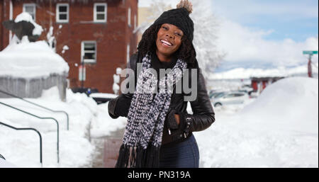 Carino donna nera gira intorno a sorridere alla telecamera fuori nella neve Foto Stock