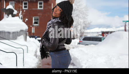 Carino donna nera gira intorno a sorridere alla telecamera fuori nella neve Foto Stock