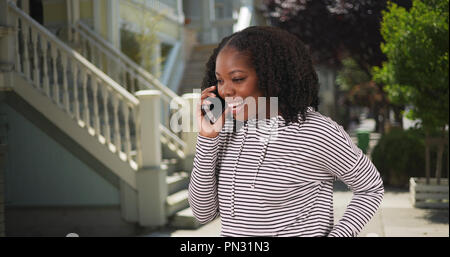 Carino donna sorridente parlando con il mio ragazzo per telefono in ambiente esterno Foto Stock