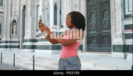 Carino donna nera prende un selfie con lo smartphone al di fuori del Duomo di Firenze Foto Stock