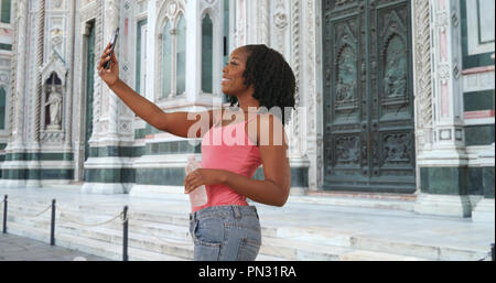 Carino femmina nero prende un selfie con lo smartphone al di fuori del Duomo di Firenze Foto Stock