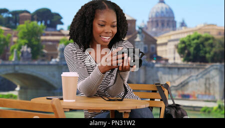 Felice nero donna guarda le foto sulla fotocamera vicino la Basilica di San Pietro Foto Stock