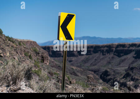 Svolta a sinistra freccia cartello stradale a switchback su una strada presso il Canyon Rim sopra il Rio Grande Gorge vicino a Taos, Nuovo Messico Foto Stock