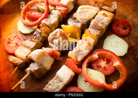 Grigliata di pezzi di carne con verdure. Brace shish kebab spiedini o su bastoni. Vista dall'alto su sfondo di legno Foto Stock