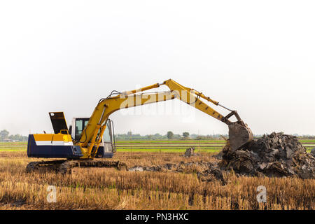 Escavatore lavoro del retroescavatore in lo scavo di un terreno per regolare le aree di postharvest in campi di riso. agricoltura macchinari per l'agricoltura moderna indus Foto Stock