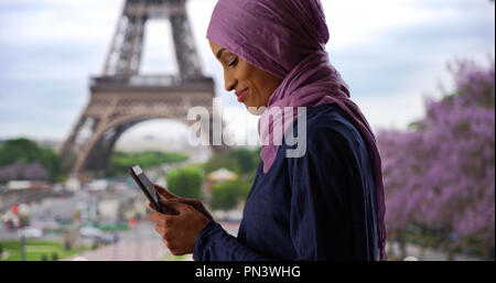 Giovane bella donna musulmana in Parigi Francia texting vicino alla Torre Eiffel Foto Stock