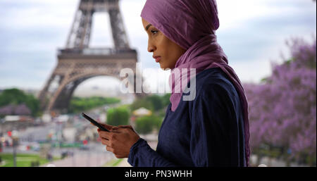 Giovane bella donna musulmana in Parigi Francia texting vicino alla Torre Eiffel Foto Stock