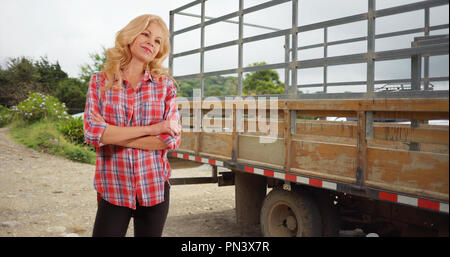 Fiero agricoltore in piedi dalla fattoria alla ricerca del carrello al di fuori della fotocamera supervisionare altri lavori Foto Stock