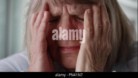 Close-up di sottolineato senior donna faccia del dolore in ambienti chiusi dentro la sua casa Foto Stock