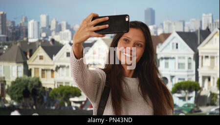 Donna millenaria con zaino prende selfie telefono in San Francisco neighborhood Foto Stock
