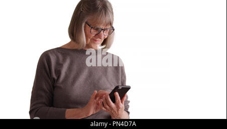 Bella donna matura utilizzando smart phone dispositivo per inviare testi su bianco spazio di copia Foto Stock