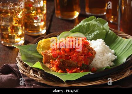 Ayam Geprek Balado. Fusion street food piatto di pollo fritto e rabboccato con sambal Lado o Sambal Oelek, il tradizionale rosso pasta di peperoncino. Foto Stock