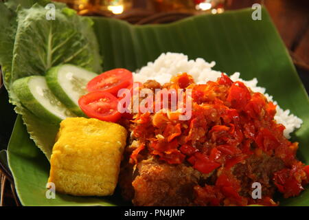 Ayam Geprek Balado. Fusion street food piatto di pollo fritto e rabboccato con sambal Lado o Sambal Oelek, il tradizionale rosso pasta di peperoncino. Foto Stock