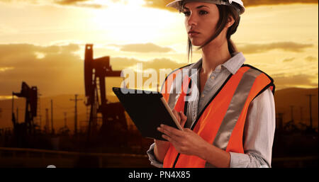 Focalizzato ingegnere femmina in un duro lavoro sul dispositivo tampone in oilfield da pumpjacks Foto Stock