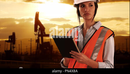 Focalizzato ingegnere femmina in un duro lavoro sul dispositivo tampone in oilfield da pumpjacks Foto Stock