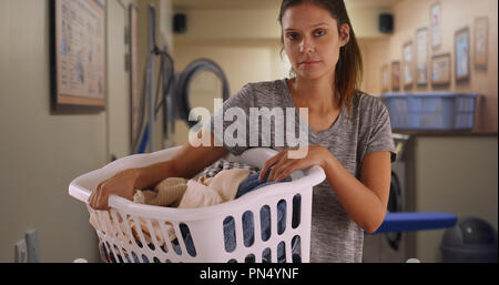 Grave giovane donna cestello di contenimento dei panni sporchi in lavanderia Foto Stock