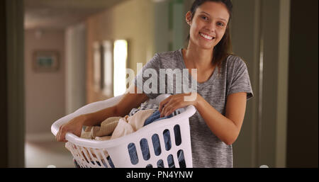 Casual ritratto di felice giovane donna a casa cestello di contenimento dei vestiti puliti Foto Stock