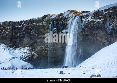 I turisti alla spettacolare cascata Seljalandsfoss nel sud dell'Islanda con glaciale acque di fusione da Eyjafjahajokul icecap Foto Stock