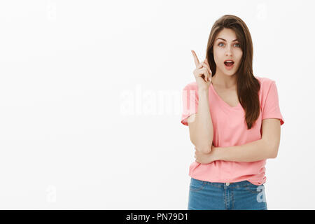 So esattamente cosa fare. Ritratto di smart e attraente brunette in rosa t-shirt, sollevando il dito indice in gesto di Eureka e guardando la telecamera, avente importrant suggerimento o piano, condivisione Foto Stock