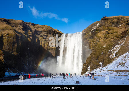 Turisti e rainbow a spettacolari cascate Skogar - Skogarfoss - nel sud dell'Islanda con fragoroso glaciale acque di fusione Foto Stock
