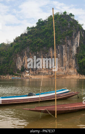 Ormeggiate barche sul fiume Mekong nella parte anteriore di una roccia calcarea dove il famoso Pak Ou Le grotte sono impostati. Essi sono situati vicino a Luang Prabang in Laos. Foto Stock