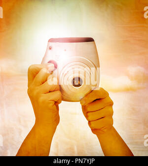 Vintage creativo effetto di colore sulle mani tenendo la fotocamera e scattare con il flash. Foto Stock