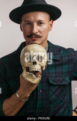 Uomo carino con tatuaggi tenendo un cranio il disegno su di esso tattoo Foto Stock