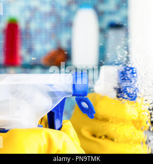 Mano in giallo guanto protettivo di spruzzatura di liquido di pulitura a specchio nella sala da bagno Foto Stock