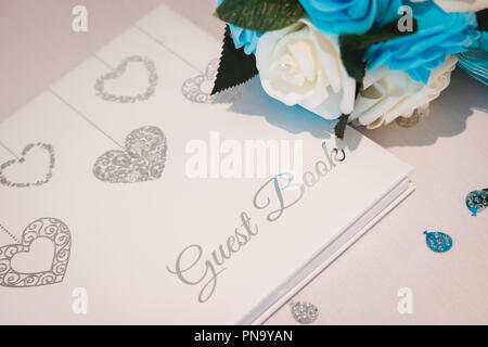 Wedding guest book prevista su bianco seta e circondato da petali di fiori Foto Stock