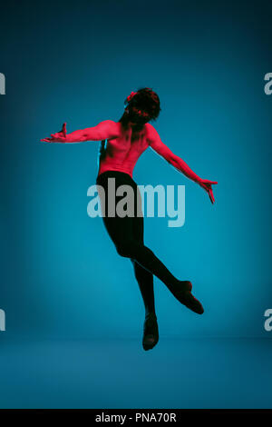 Il maschio athletic ballerina di eseguire la danza sul vivace sfondo blu. Studio shot. Balletto moderno, contemporaneo concetto. Montare il giovane. Modello del Caucaso Foto Stock