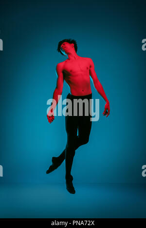 Il maschio athletic ballerina di eseguire la danza sul vivace sfondo blu. Studio shot. Balletto moderno, contemporaneo concetto. Montare il giovane. Modello del Caucaso Foto Stock