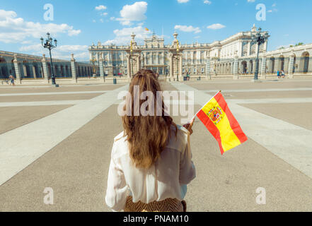 Visto da dietro il viaggiatore moderno donna con la bandiera della Spagna contro la Royal Palace Foto Stock