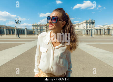 Ritratto di sorridente giovane viaggiatore donna vicino Palazzo Reale esaminando la distanza Foto Stock