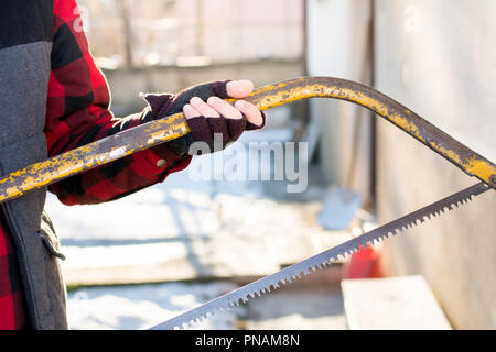 Uomo con una sega a mano per il taglio di legno in cantiere Foto